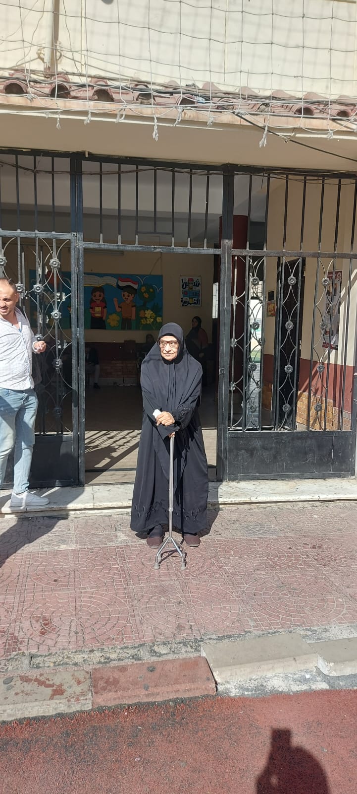 1764071008 724 سيدة مسنّة تتحدى الصعوبات وتشارك في الانتخابات بالعكاز